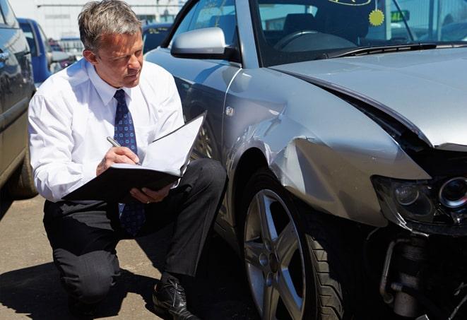 car accident scene with insurance adjuster inspecting damage